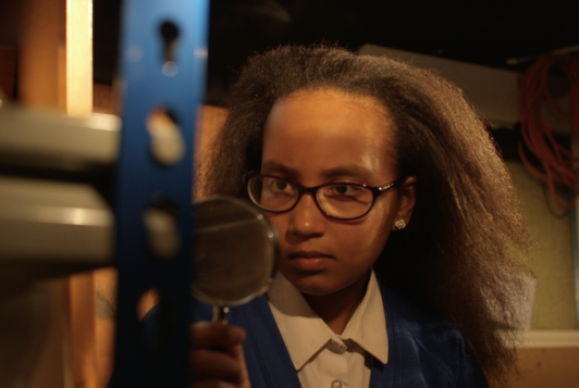 Black girls looking through a magnifying glass